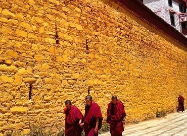 Monks under yelloe wall at Ganden Monastery