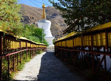 An alley of prayer wheels leading up to a pagoda.